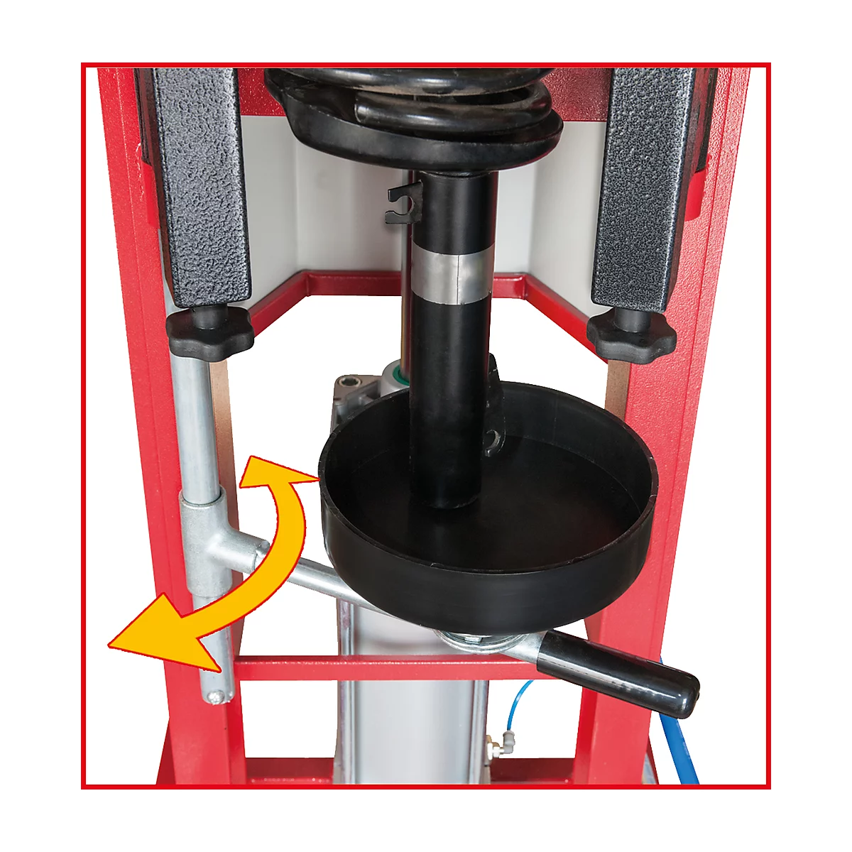 Hydraulische Federbeinpresse; schwarze Feder mit schwarzem Teller; roter Rahmen; gelber Pfeil zeigt die Bewegung an.